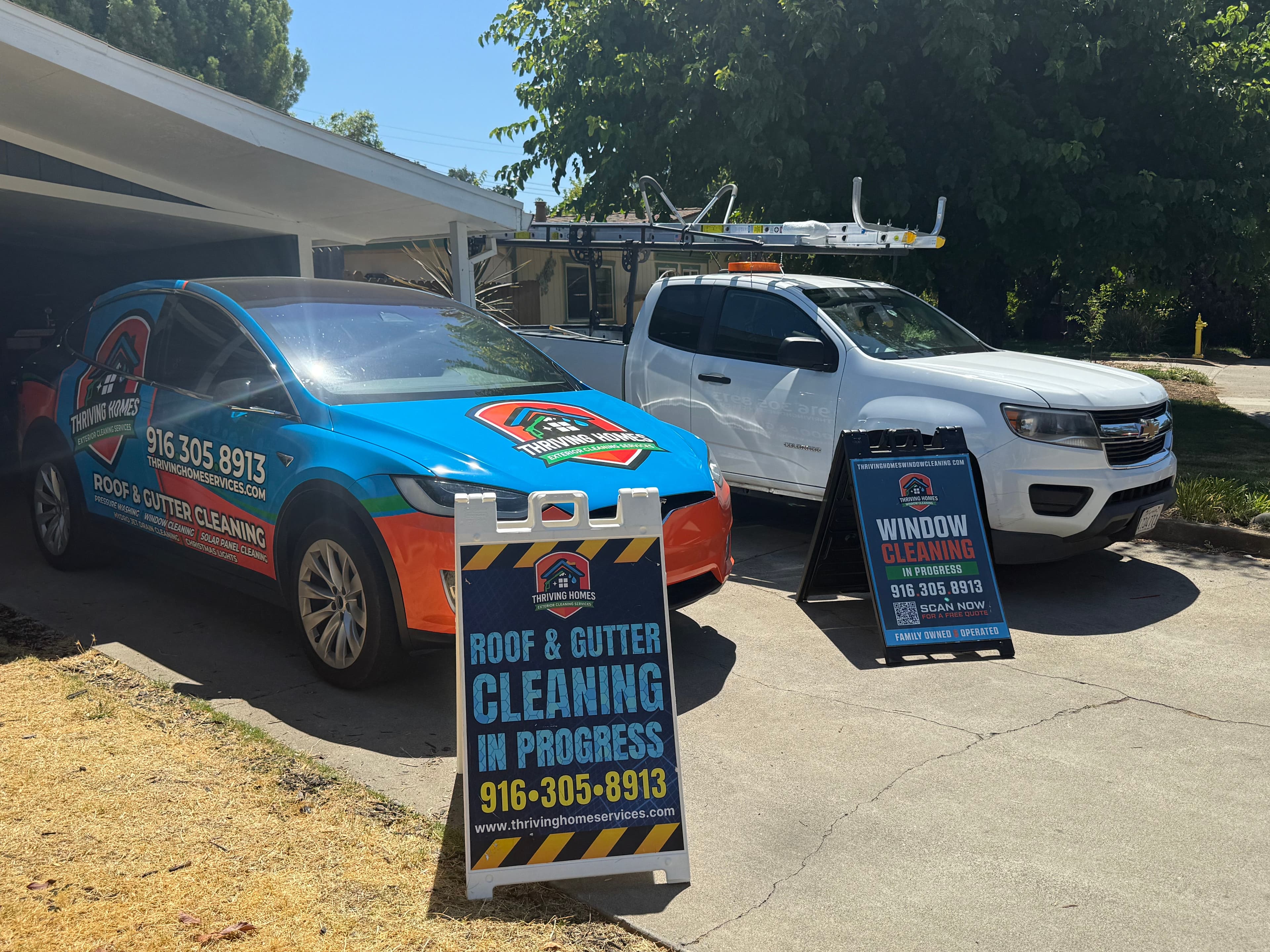 Cars with branding for roof and gutter cleaning, plus window cleaning signs in a driveway.